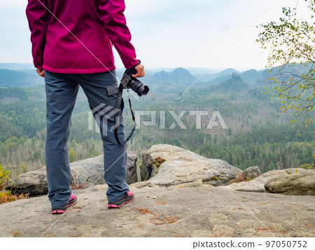 Woman photographer on cliff. Nature photographer hand holds mirror camera Woman photographer on cliff. Nature photographer hand holds mirror camera 97050752
