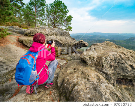 Travel hike woman sit on heels and taking photo with phone. Travel hike woman sit on heels and taking photo with phone. 97050753