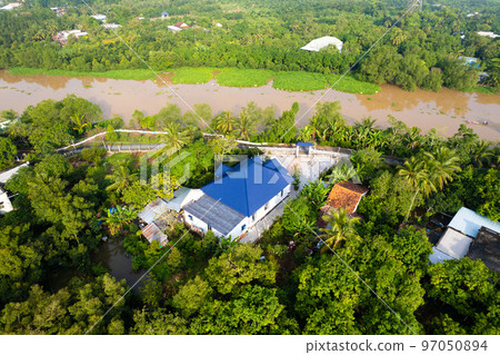 aerial view of Villa house in the middle of the garden with blue tile roof and the river at Mekong river delta VietNam countryside, Thai house building style.  97050894
