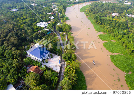 aerial view of Villa house in the middle of the garden with blue tile roof and the river at Mekong river delta VietNam countryside, Thai house building style. aerial view of Villa house in the middle of the garden with blue tile roof and the river at Mekong river delta VietNam countryside, Thai house building style. 97050896