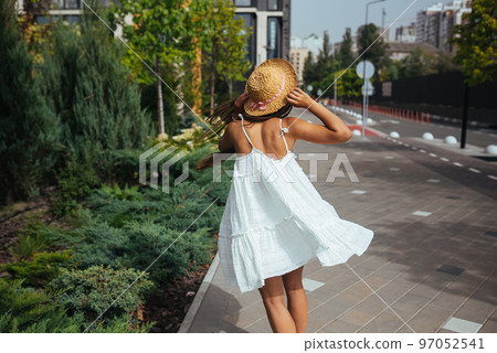 Beautiful in a white dress poses on the street Beautiful in a white dress poses on the street 97052541