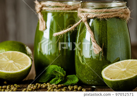 Closeup of fresh green smoothie in glass jars with lime. Detox concept. Good food Closeup of fresh green smoothie in glass jars with lime. Detox concept. Good food 97052571