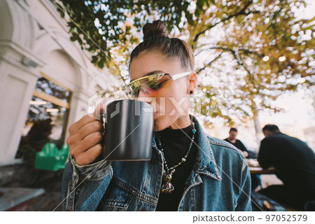 Cute young woman while drinking tea in modern street cafe 97052579