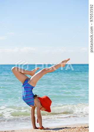 Teenage girl stay on hands at beach 97053592