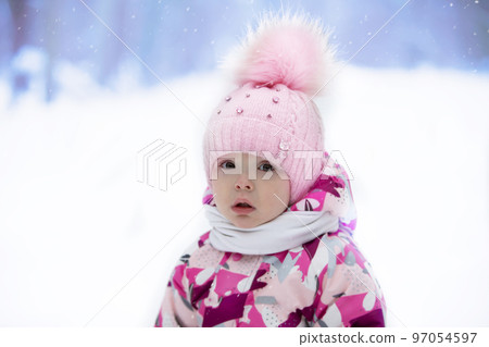 Portrait of a little girl in a winter hat on the background of winter nature. Child in winter. 97054597