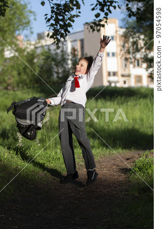A happy schoolboy throws up his school backpack and rejoices at the start of the holidays. The end of the school year and the beginning of the holidays. A happy schoolboy throws up his school backpack and rejoices at the start of the holidays. The end of the school year and the beginning of the holidays. 97054598