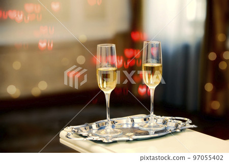 Two glasses of champagne against a background of bokeh spots. Festive romantic background. Two glasses of champagne against a background of bokeh spots. Festive romantic background. 97055402