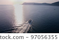 White luxury yacht sails on the ocean. Shooting from a drone as a small light sea vessel, leaving a trail of foam and waves along the sea dark water surface 97056355