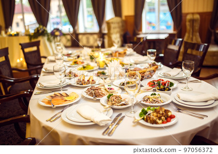 Wedding table in the restaurant decorated with white candles and flowers. 97056372