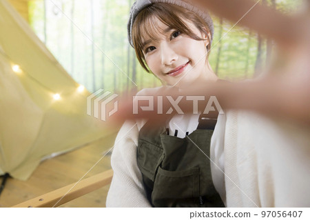 坐在戶外椅子上揮手的年輕女子 97056407