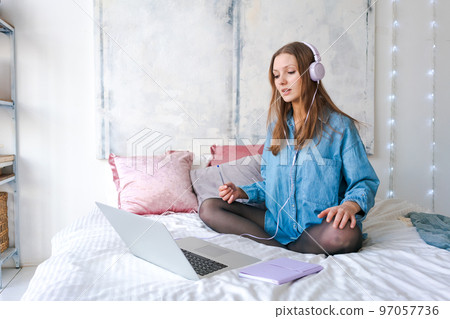 Portrait young joyful woman in home clothes, at laptop studying online or 97057736