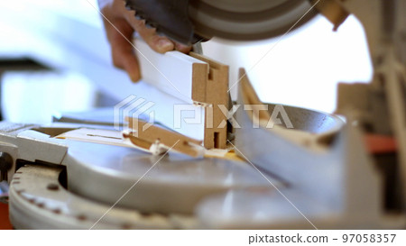 Close-up of a male master with a grinding machine for cutting cuts off a profile. Macro 97058357