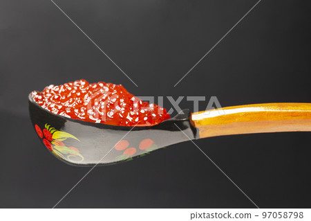 Delicious red caviar in wooden spoon on black background 97058798