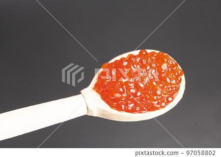 Delicious red caviar in wooden spoon on black background Delicious red caviar in wooden spoon on black background 97058802