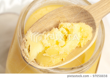 Ghee in jar and wooden spoon isolated on white background 97058838