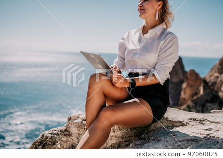 Digital nomad, Business woman working on tablet pc pad computer by the sea. Pretty lady with tablet pc on the sea, makes a business transaction online from distance. Freelance, remote work on vacation 97060025