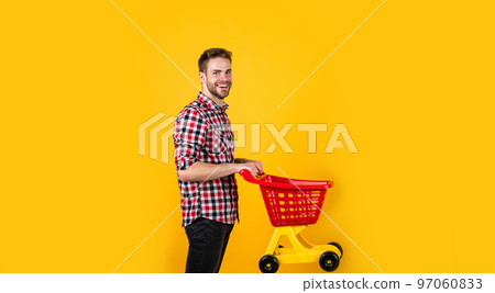 man go shopping. funny man with small shopping cart. weekend on buying products. rejoices successful purchases. spends money unwisely. customer pushing cart. buyer in supermarket. empty toy trolley 97060833