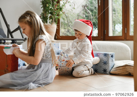 The brother and sister unwrapping christmas presents The brother and sister unwrapping christmas presents 97062926