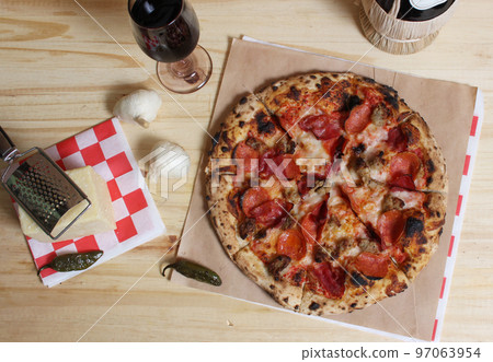 Fresh Pizza on Wooden Table at Restaurant With Bottle of Chianti Wine in Background 97063954