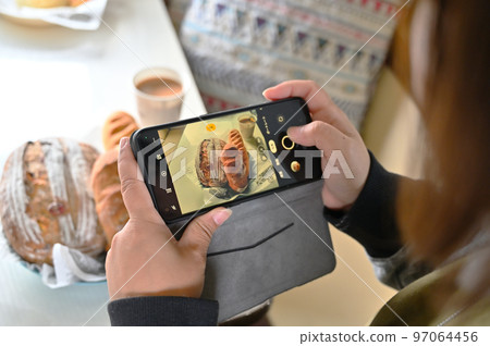 一位女士用她的智能手機 Deli 麵包在露營車裡時尚地拍攝一頓飯 一位女士用她的智能手機 Deli 麵包在露營車裡時尚地拍攝一頓飯 97064456