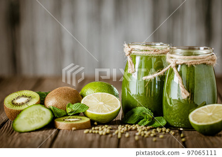 Blended green smoothie with ingredients on the wooden table selective focus. Healthy food.  97065111