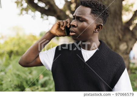 Young African man talking on phone shocked, stressed. Street portrait, copy space 97066579
