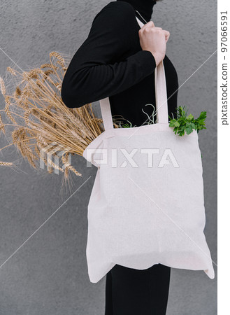 Young girl holding a cloth bag with ears of wheat 97066591