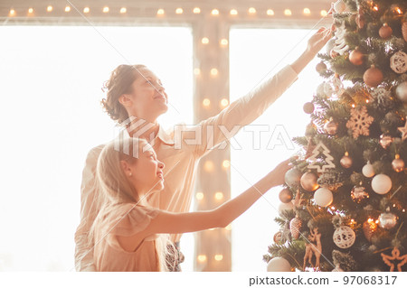 happy mom and little daughter decorating the Christmas tree happy mom and little daughter decorating the Christmas tree 97068317