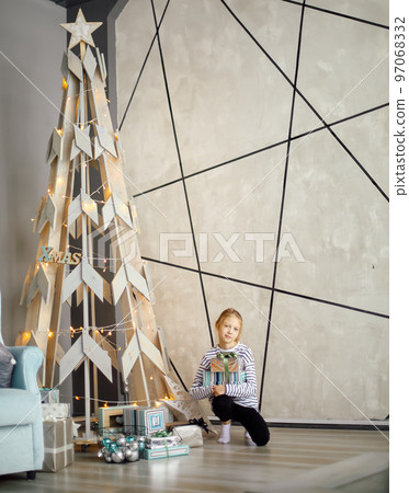 little girl sitting near a stylized Christmas tree. little girl sitting near a stylized Christmas tree. 97068332