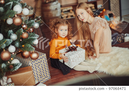 two pretty sisters sitting on the floor on Christmas eve two pretty sisters sitting on the floor on Christmas eve 97068471