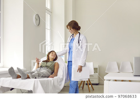 Happy child having medical checkup, lying on examination couch and talking to doctor Happy child having medical checkup, lying on examination couch and talking to doctor 97068633