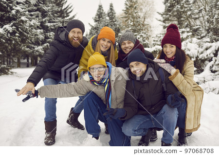 Smiling friends enjoy winter holidays in snowy park Smiling friends enjoy winter holidays in snowy park 97068708