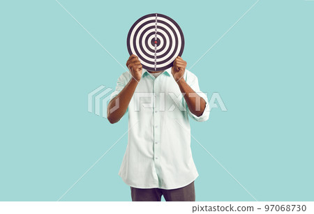 Anonymous man hides face behind dart board, symbolizing selection of target audience or targeted ads 97068730