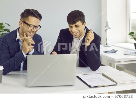 Two happy successful business people using laptop computer while working in the office 97068738