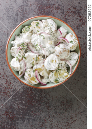 Farskpotatissallad is a traditional Swedish salad with a combination of new potatoes, sour cream or creme fraiche, chopped dill, and onion close-up in a plate. Vertical top view Farskpotatissallad is a traditional Swedish salad with a combination of new potatoes, sour cream or creme fraiche, chopped dill, and onion close-up in a plate. Vertical top view 97068962