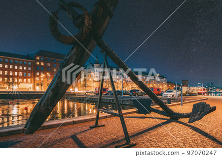 Helsinki, Finland. Old Anchor On Pier With View Of Pohjoisranta Street In Evening Night Illuminations. Colourful Night Starry Sky In Dark Blue Colors. Sky Glowing Stars Background With Sky Gradient 97070247