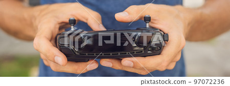 Man holds remote controller with his hands and controls the drone. New technologies and innovations concept BANNER long format 97072236