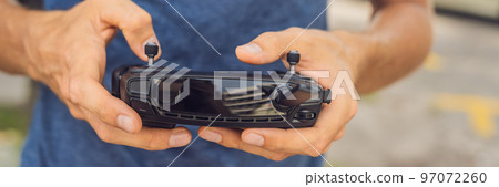 Man holds remote controller with his hands and controls the drone. New technologies and innovations concept BANNER long format 97072260