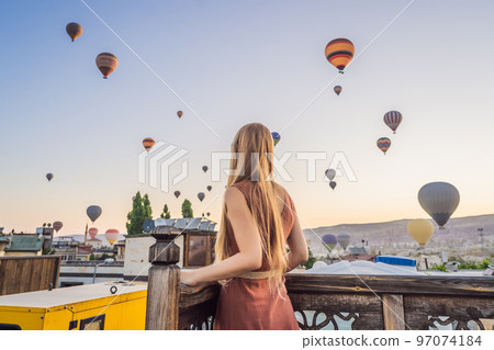Tourist woman looking at hot air balloons in Cappadocia, Turkey. Happy Travel in Turkey concept. Woman on a mountain top enjoying wonderful view 97074184