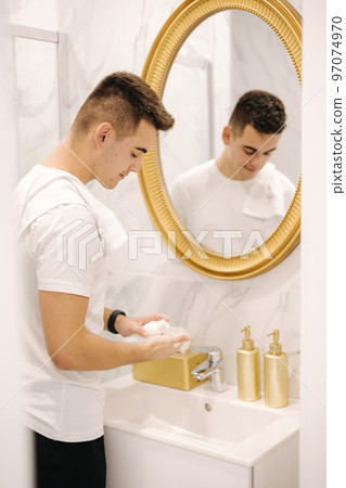 Man using cream for hands and face at home in the bathroom. Keep clean concept 97074970