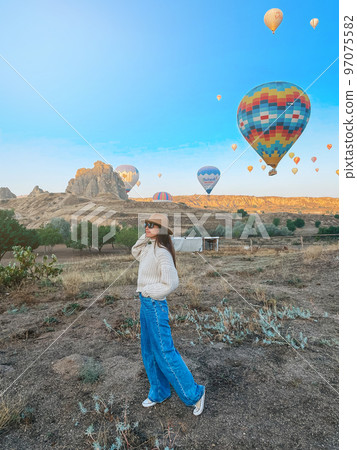 Happy woman during sunrise watching hot air balloons in Cappadocia, Turkey 97075582