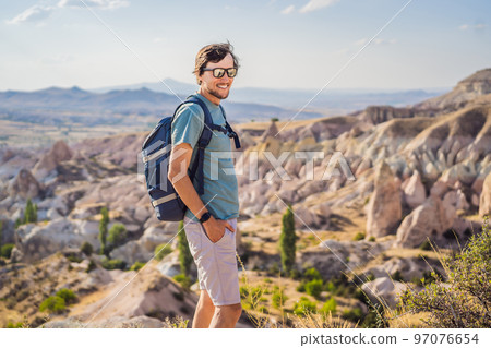 Young man exploring valley with rock formations and fairy caves near Goreme in Cappadocia Turkey Young man exploring valley with rock formations and fairy caves near Goreme in Cappadocia Turkey 97076654