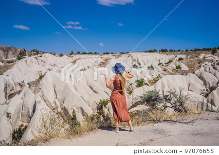 Young woman exploring valley with rock formations and fairy caves near Goreme in Cappadocia Turkey 97076658