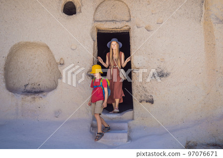 Mom and son tourists exploring valley with rock formations and fairy caves near Goreme in Cappadocia Turkey 97076671