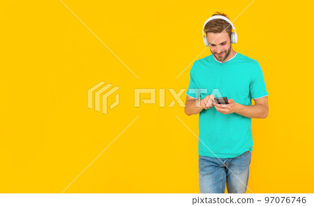 Happy young man chatting on mobile phone listening to digital music in headphones, chat 97076746