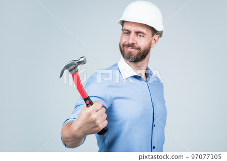 handsome smiling bearded businessman in helmet hold hammer, repairing handsome smiling bearded businessman in helmet hold hammer, repairing 97077105
