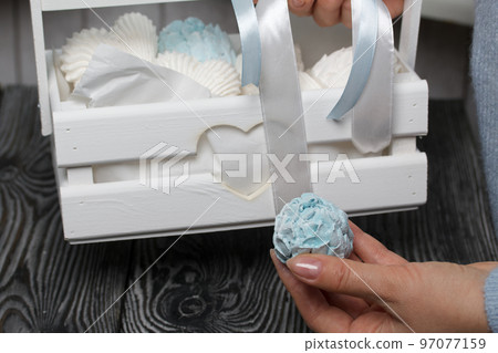 Marshmallow cones. Homemade zeohyr. The woman puts it in a wooden decorative box. On the background of the boards. Close-up. Marshmallow cones. Homemade zeohyr. The woman puts it in a wooden decorative box. On the background of the boards. Close-up. 97077159