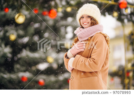 Young woman in winter style clothes posing at festive street market. Cold weather. Winter fashion. Young woman in winter style clothes posing at festive street market. Cold weather. Winter fashion. 97078993