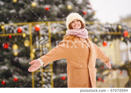 Young woman in winter style clothes posing at festive street market. Cold weather. Winter fashion. 97078994