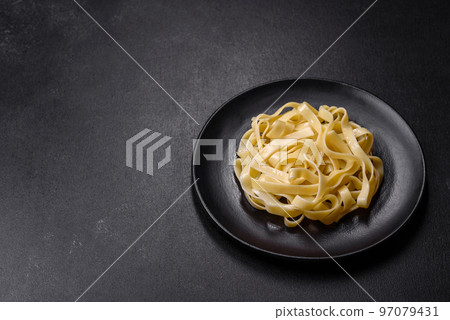 Delicious fresh pasta with pesto sauce and seafood on a black plate Delicious fresh pasta with pesto sauce and seafood on a black plate 97079431